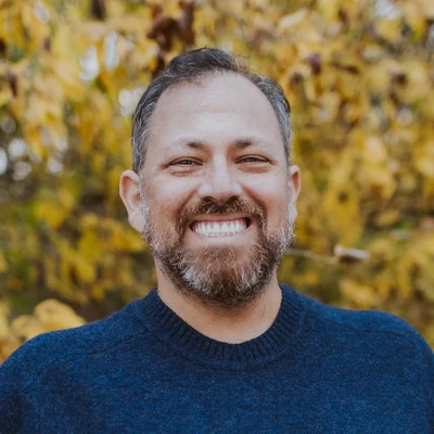 Mike Kerklin smiling outdoors in front of yellow fall leaves