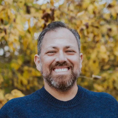 Mike Kerklin headshot, smiling outdoors in front of fall leaves
